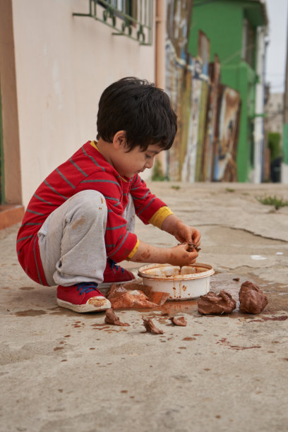 穿着红衬衫跪着的男孩用粘土做人形。黏土。粘土会话图片下载
