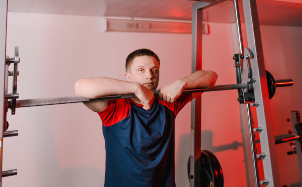 一个疲惫的运动员站在体操房里的杠铃旁的大肖像。训练后休息图片下载