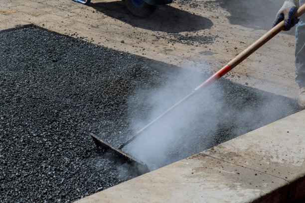 工人在铺设沥青新路面时修补沥青覆盖物图片下载