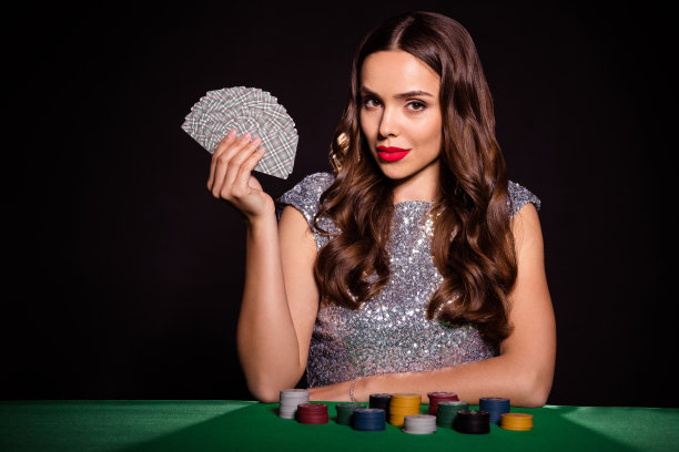 照片中的神秘女士坐在赌场的桌子上，手持扇子牌，穿着优雅的服装孤立的黑色背景图片下载