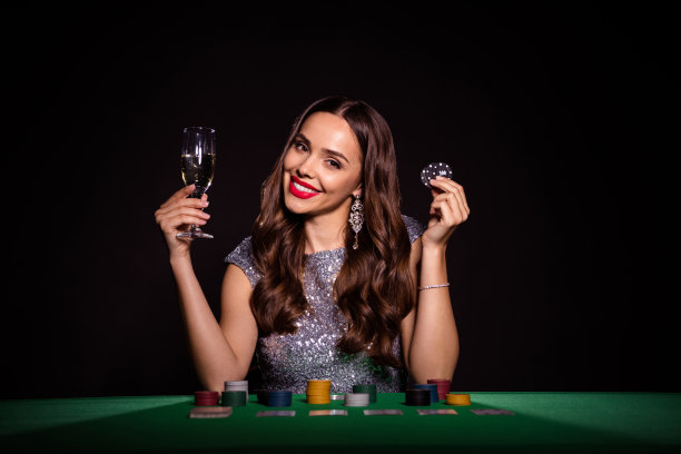 迷人的快乐的好女人的照片坐在扑克桌子持有扑克筹码香槟孤立的黑色背景图片下载