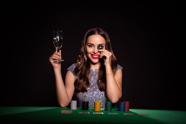 女士的照片，坐扑克桌，持有玻璃香槟芯片，盖眼睛，穿着光泽的衣服孤立的黑色背景图片下载