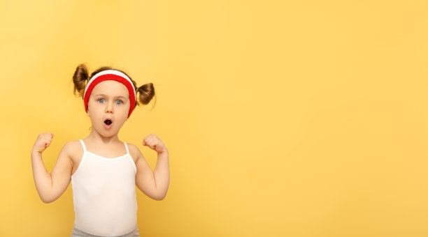 兴奋的健身孩子摆姿势在运动服，红色腕带，头带在黄色演播室背景。儿童体育、广告、购物的概念。健身房锻炼。童年的活动。运动。健康和活力图片下载