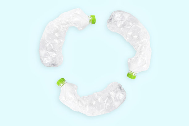 蓝色背景上的三个破碎的塑料瓶形成再循环标志。图片下载