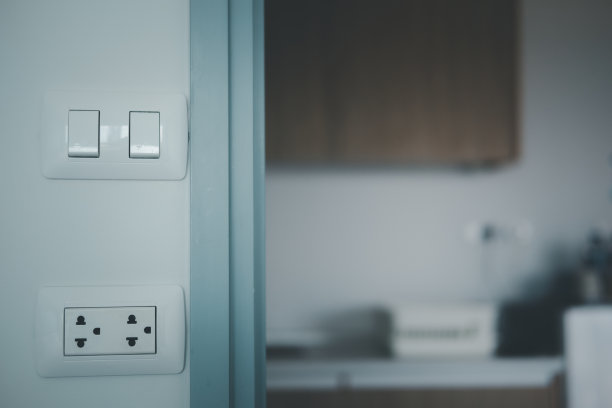 一组白色插座和一个开关位于现代厨房前的灰色墙壁上图片下载