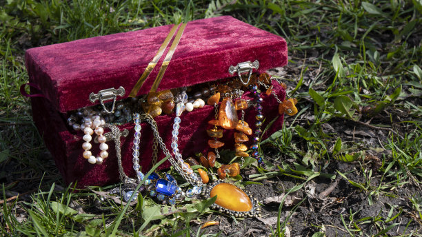 经典的红丝绒半闭胸，缀满闪闪发光的珠宝，伫立在阳光下的草地上。复古的成分。图片下载