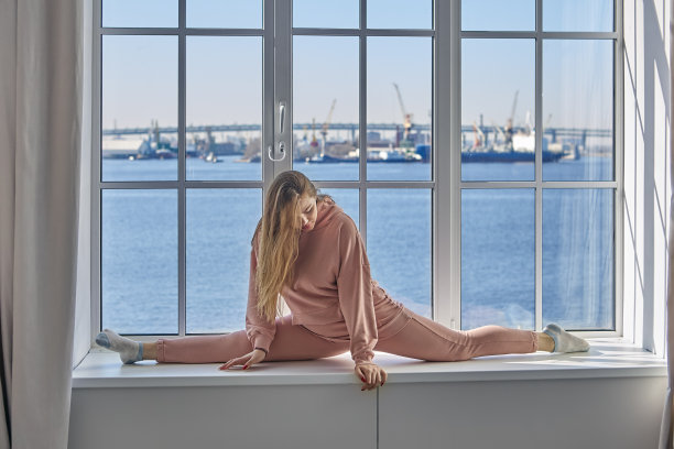 拉拉队女孩的家庭锻炼，柔韧的年轻女子做伸展运动做劈叉。图片下载