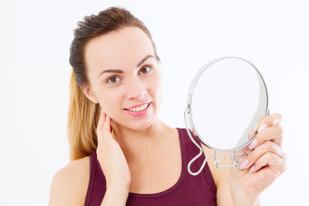 年轻的白人妇女看皱纹在镜子孤立在白色的背景。护肤、抗衰老和化妆理念。本空间图片下载