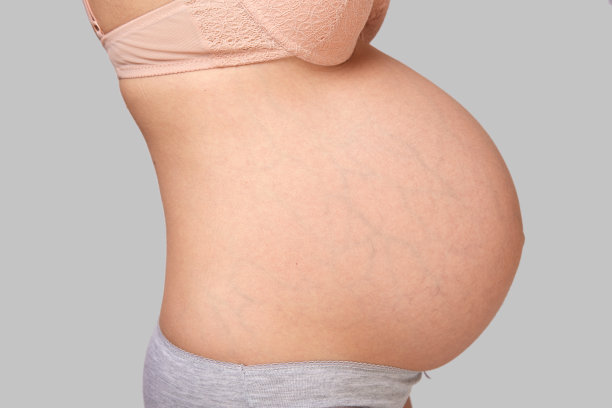 一个穿着内衣的孕妇的身体在一个灰色孤立的背景。医学和美容的概念。图片下载