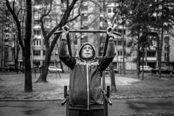 运动的老年人在寒冷的雨天做引体向上。图片下载