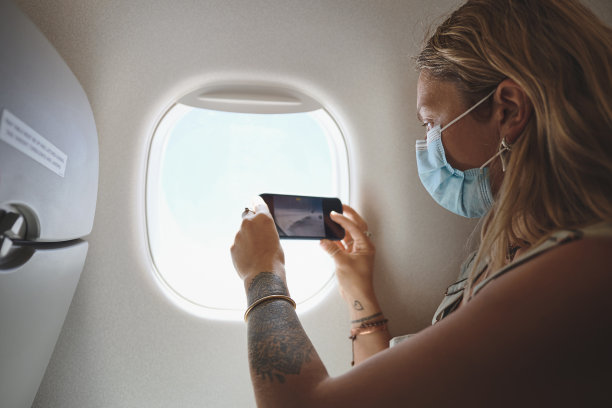 这是一名年轻女子在飞机上靠窗的座位上拍摄风景的照片图片下载