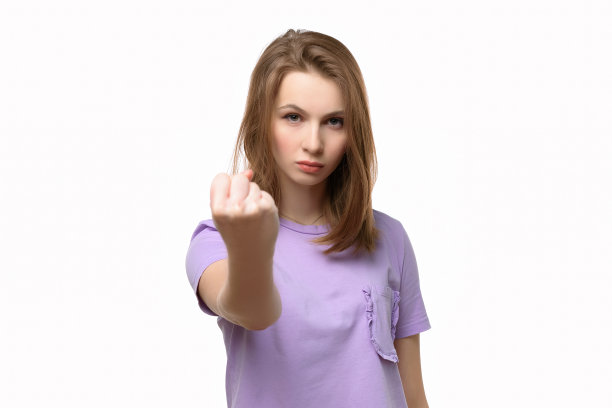 愤怒严肃的女孩看着相机显示拳头孤立在白色的背景图片下载