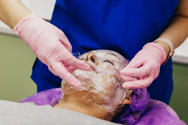 美容师正在病人脸上涂抹麻醉霜，肖像特写。图片下载