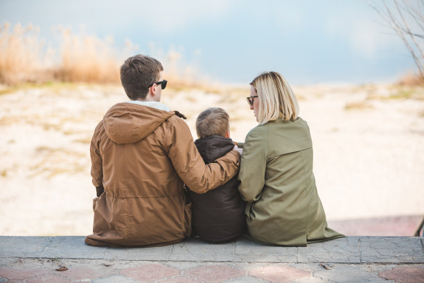 年轻美丽的家庭坐在海滩和风景湖图片下载