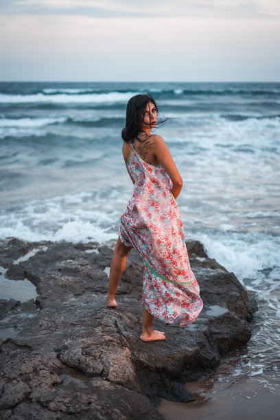 一名深色头发的白种人穿着白色织物连衣裙，在海边享受假期图片下载