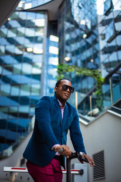 非裔美国商人骑着电动车在城市里。图片下载