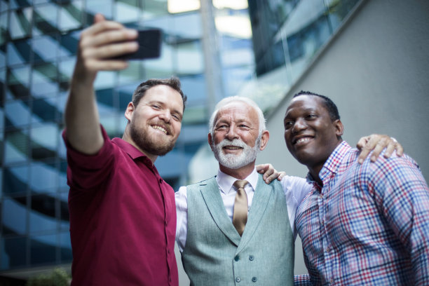 三个商人站在外面使用手机。图片下载