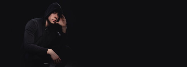 一个戴兜帽的男人的画室肖像，阴影遮住了他的脸。匿名、影子经济和逃避法律图片下载