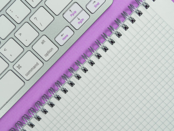 工作场所。粉红色背景上的办公室构思。键盘和记事本。平的。图片下载