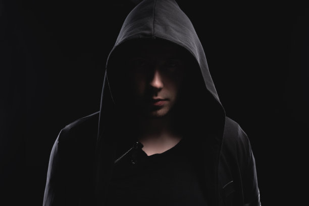 一个戴兜帽的男人的画室肖像，阴影遮住了他的脸。匿名、影子经济和逃避法律图片下载
