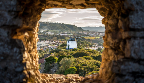 葡萄牙奥比多斯城堡墙上的小窗，古老的风车。傍晚的阳光图片下载