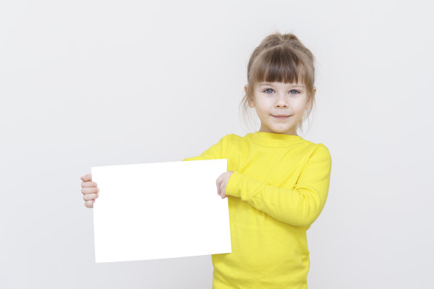 一个4岁的白人女孩穿着黄色毛衣，手里拿着一个白色的模型。图片下载