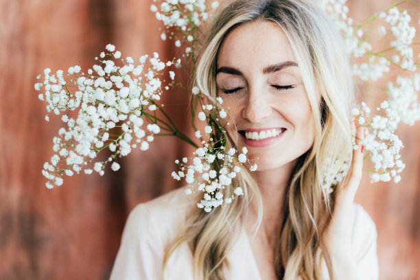 特写肖像年轻女子笑着与gypsophila在头上。图片下载