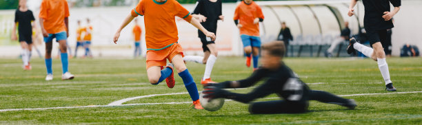 青年运动员在草地体育场踢足球比赛。孩子们踢足球。男孩们在草地上踢足球。足球长椅的背景。青年足球锦标赛图片下载