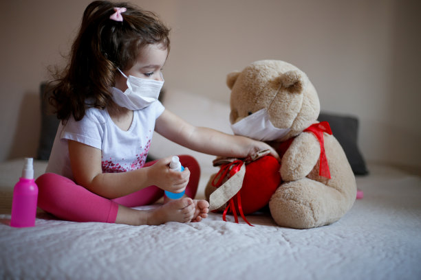 带着医用口罩的小女孩和毛绒熊。儿童疾病的概念，同情、支持和帮助患病儿童的照片图片下载