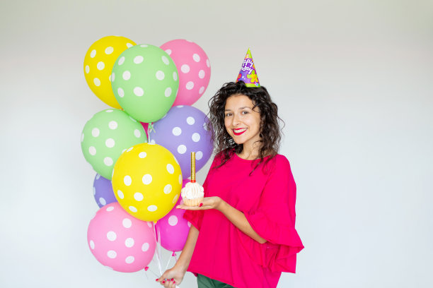 生日快乐。性感的黑发女孩与气球，烟花，彩色的气球和节日蛋糕在白色的背景图片下载