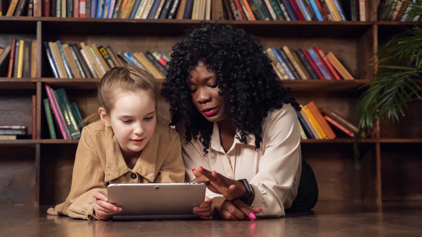 一位黑人女士用平板电脑和一名女学生交谈并展示照片图片下载