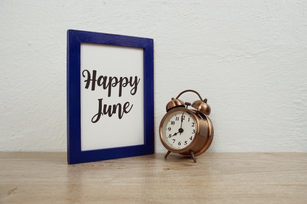 快乐六月印刷文本和闹钟木制桌子和白色的墙背景图片下载