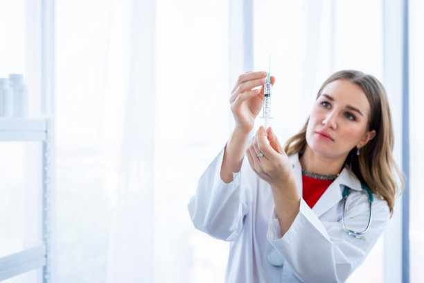 带听诊器手持注射器的女医生在医院背景图片下载