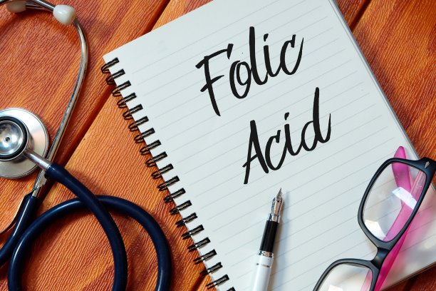 听诊器俯视图，粉红色眼镜，在木制背景上写有叶酸的笔和笔记本。健康的概念。图片下载