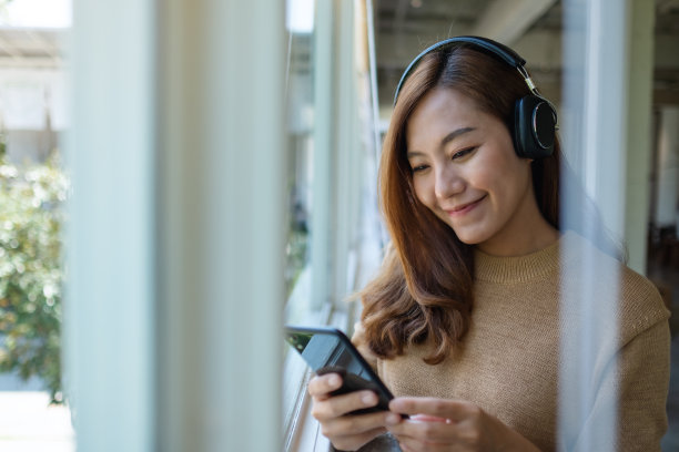 一个戴耳机的女人喜欢用智能手机听音乐图片下载