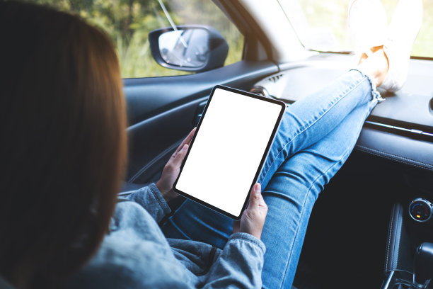 一个女人在车里拿着并使用着黑屏的平板电脑图片下载