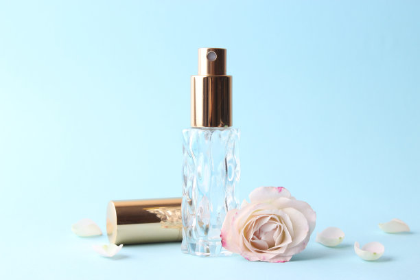 香水瓶和玫瑰花在一个光背景近距离图片下载