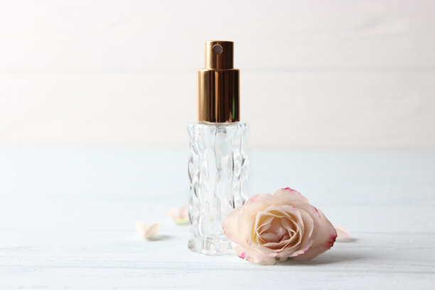 香水瓶和玫瑰花在一个光背景近距离图片下载