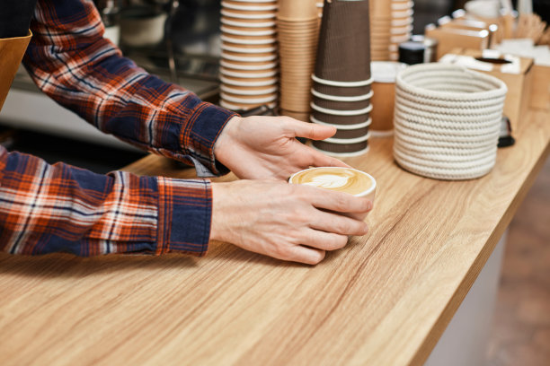 男服务员穿着围裙，端着一杯热饮图片下载