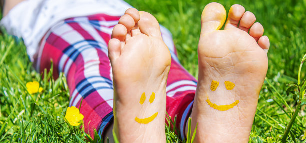 孩子们的脚上画着一幅微笑的绿色草地。有选择性的重点。图片下载