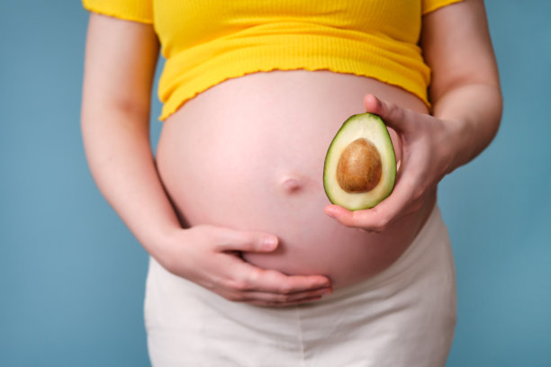 蓝色背景上一个孕妇手里拿着牛油果和一根骨头图片下载