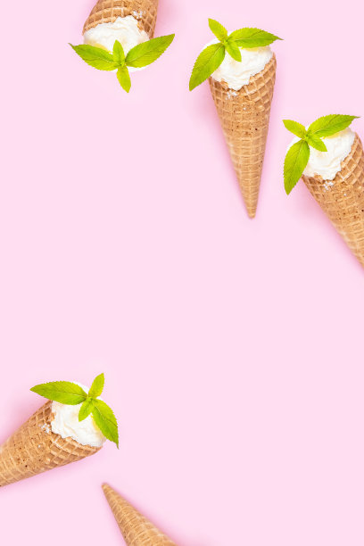 薄荷香草冰淇淋在一个华夫蛋筒，薄荷叶在粉红色的普通背景。图片下载