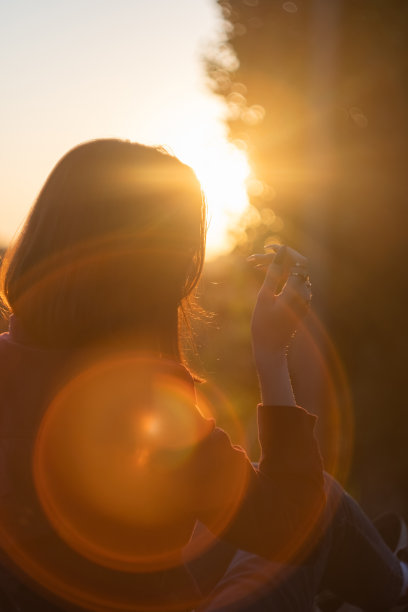 一个年轻女子在美丽的日落上放松的剪影。图片下载