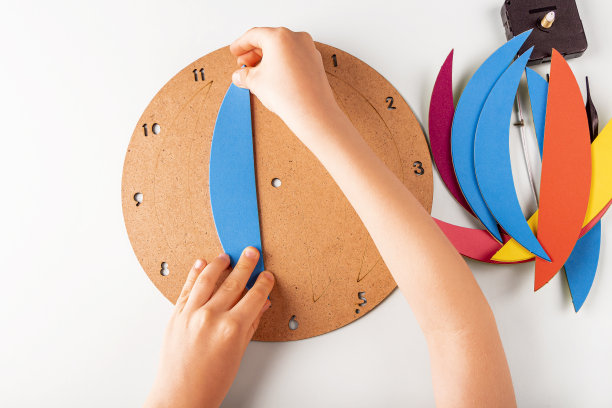 DIY和孩子的创造力。一步一步讲解:如何挂钟。步骤3儿童的手胶彩色部分到木面板。孩子工艺车间。图片下载