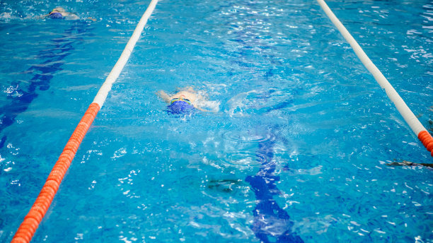 男孩在游泳池里仰泳比赛图片下载