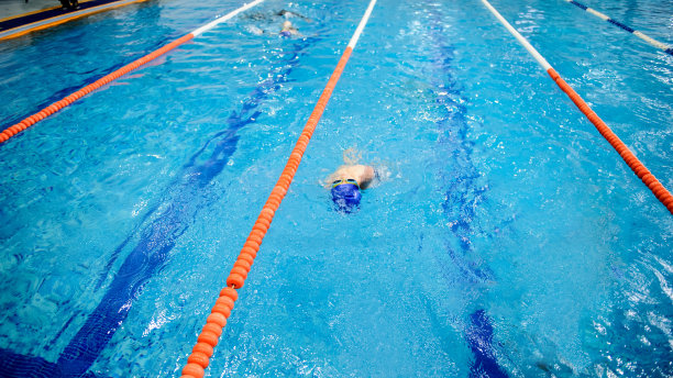 男孩在游泳池里仰泳比赛图片下载