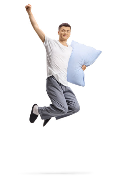 穿着睡衣抱着枕头跳起来的快乐男人图片下载