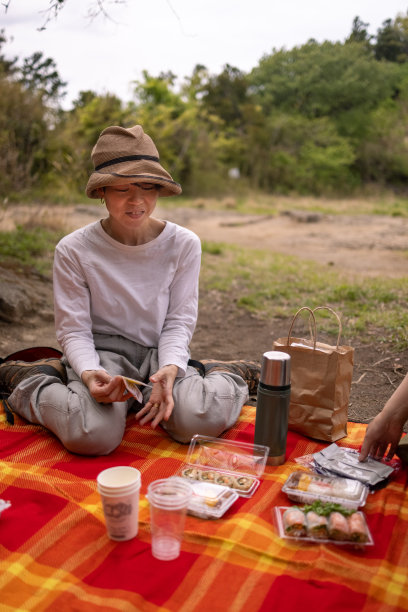 坐在野餐毯子上吃午餐的日本妇女图片下载