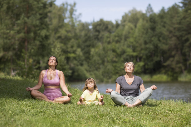 一家人的母亲、小女儿和奶奶一起在湖边练瑜伽。健康的生活方式的概念。户外活动。大流行后的新常态生活图片下载