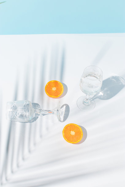 在蓝色和灰色的背景上，用新鲜的橘片、眼镜和棕榈枝构成的夏日创作。冷饮或茶点概念。图片下载